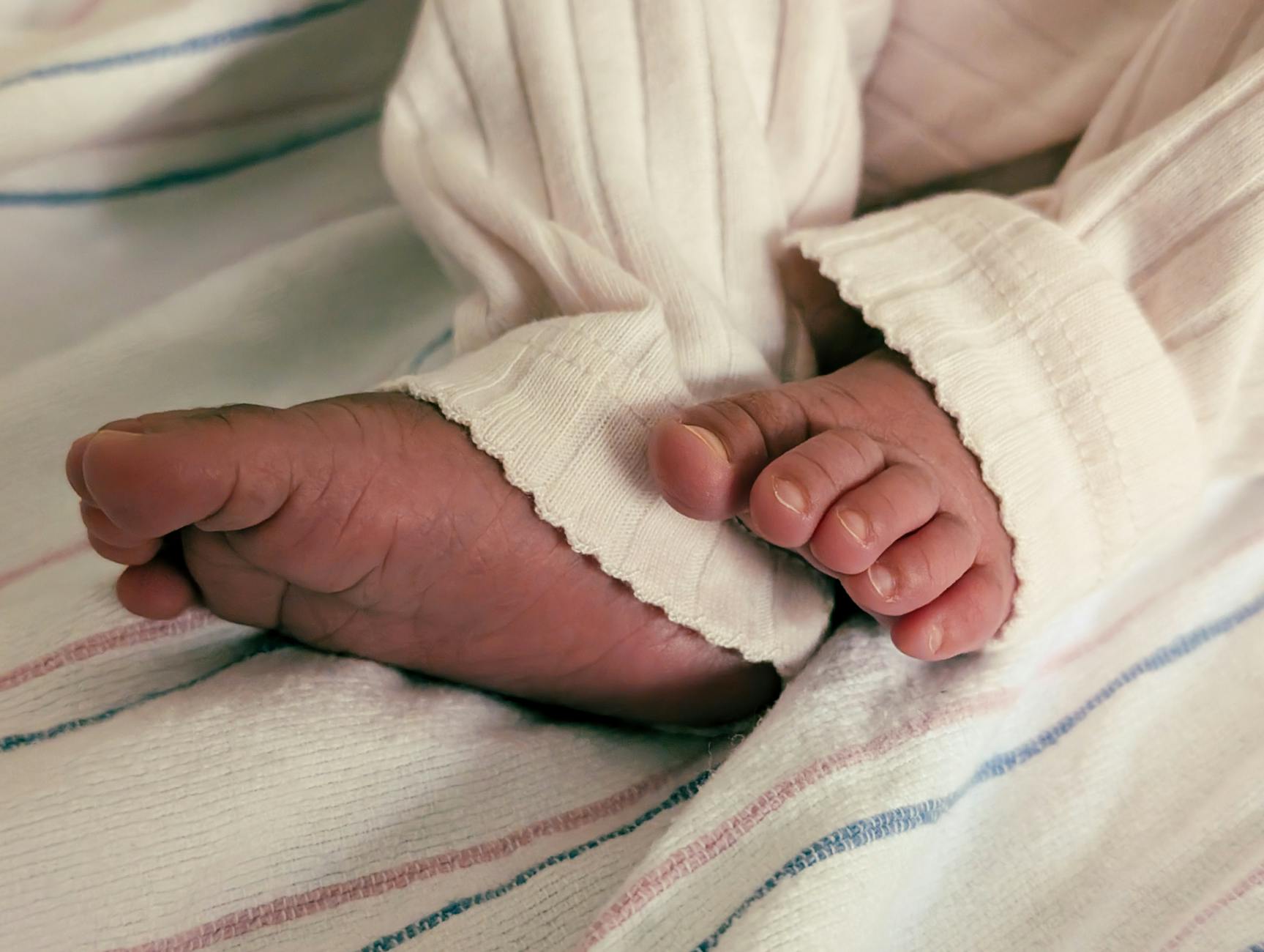 Stópki noworodka w miękkim, pasiastym pajacyku