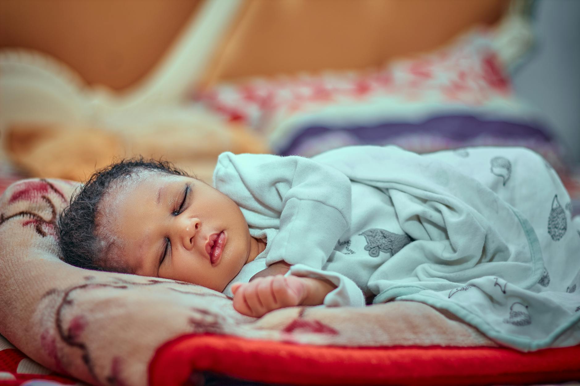Śpiące niemowlę otulone kocykiem, odpoczywające po szczepieniu