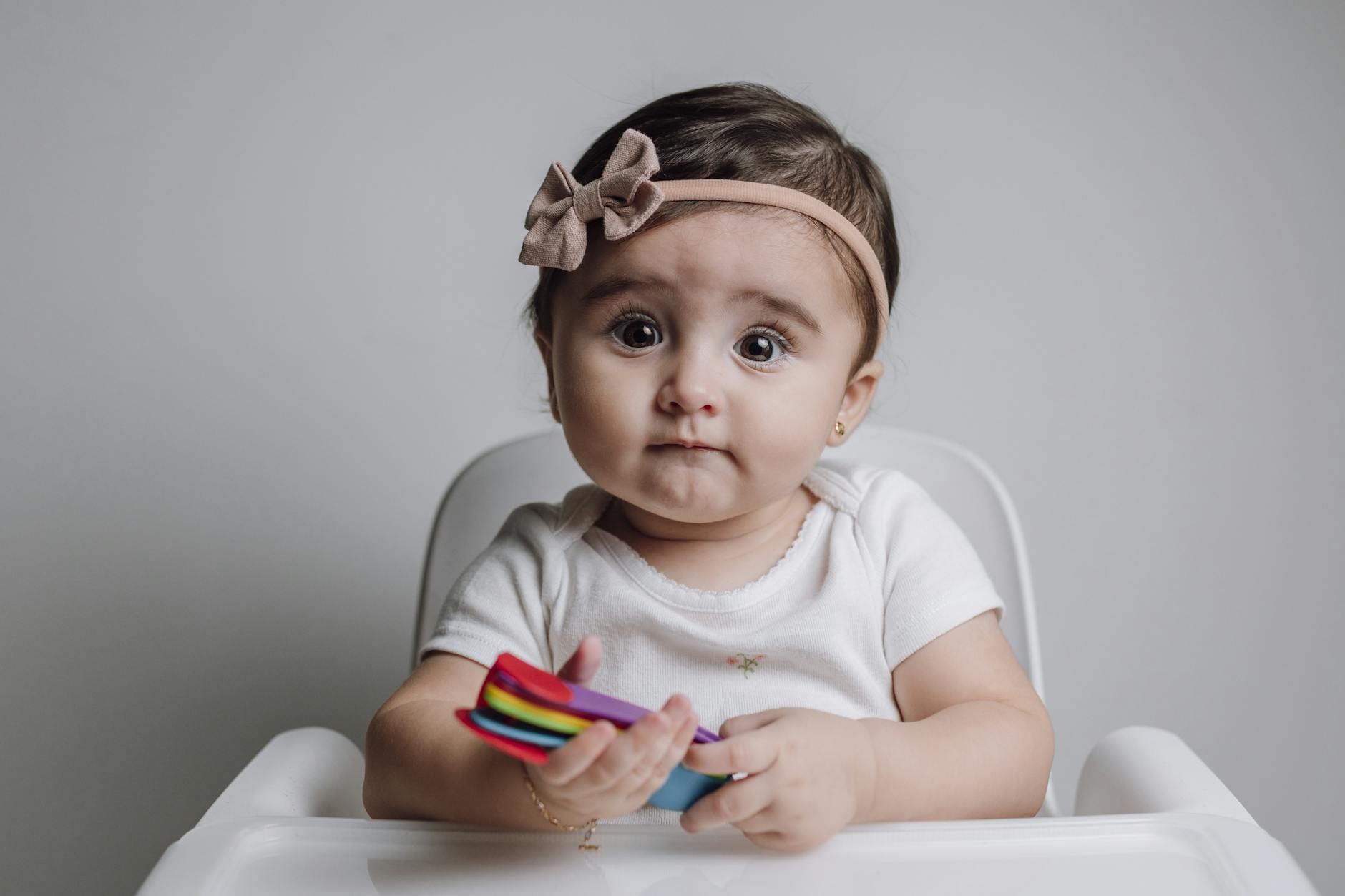 Niemowlę w wysokim krzesełku bawi się zabawką, studio fotograficzne