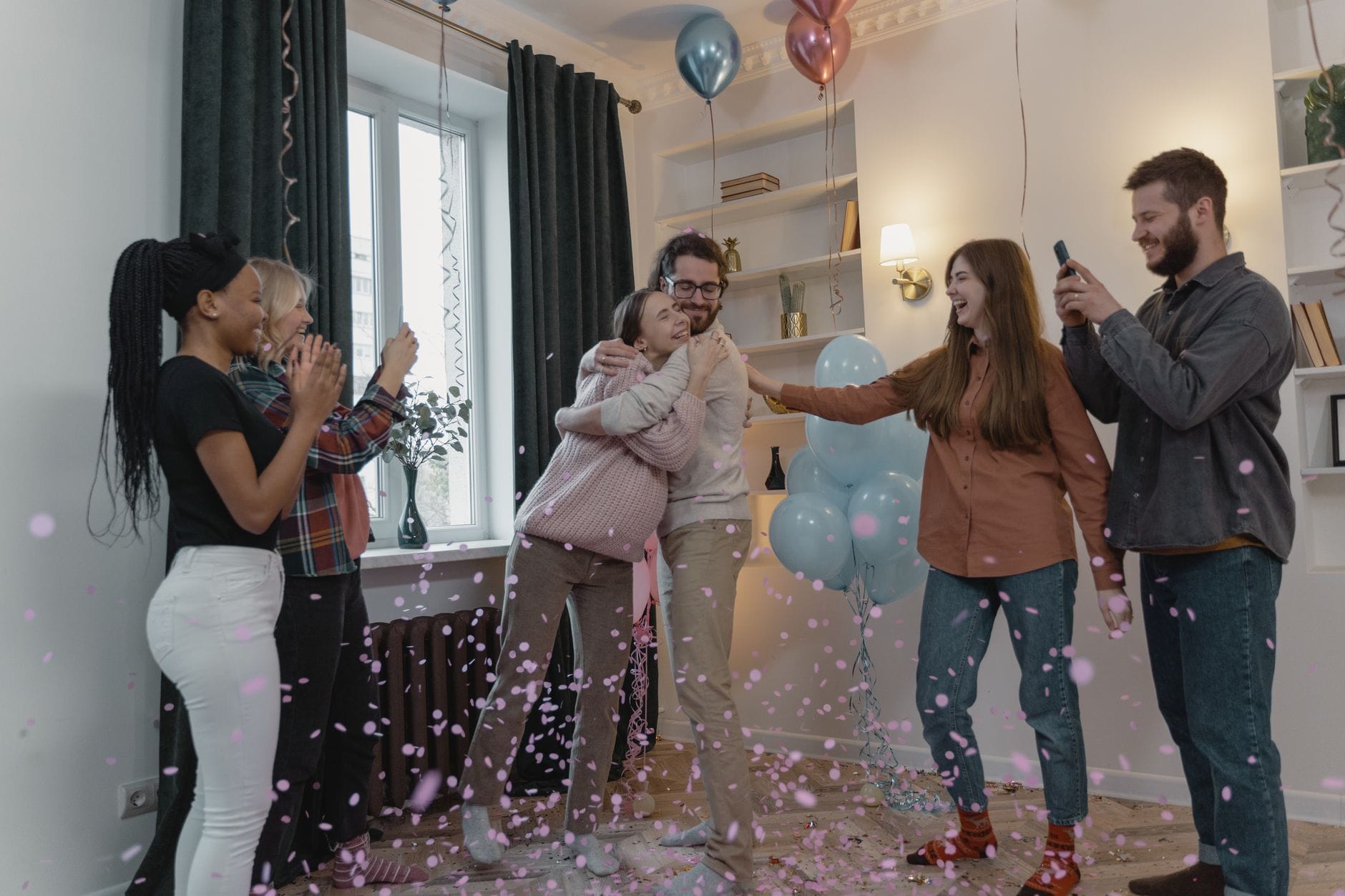 Przyjaciele świętują baby shower z balonami i konfetti w salonie