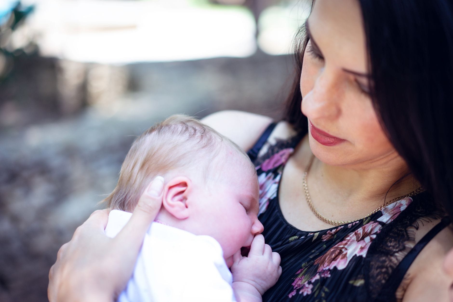 Mama tuląca śpiącego noworodka na świeżym powietrzu
