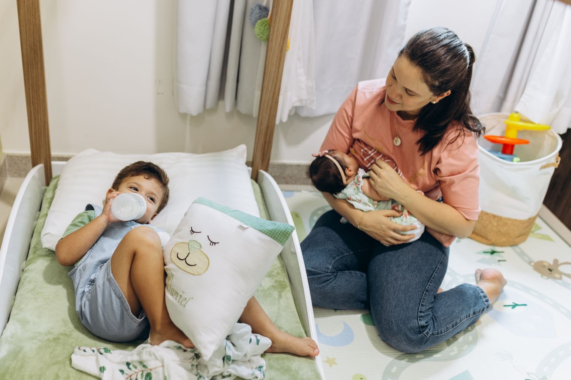 Laktator ręczny czy elektryczny: co lepiej sprawdzi się w wyprawce młodej mamy Mama z niemowlęciem i starszym dzieckiem w przytulnym pokoju dziecięcym