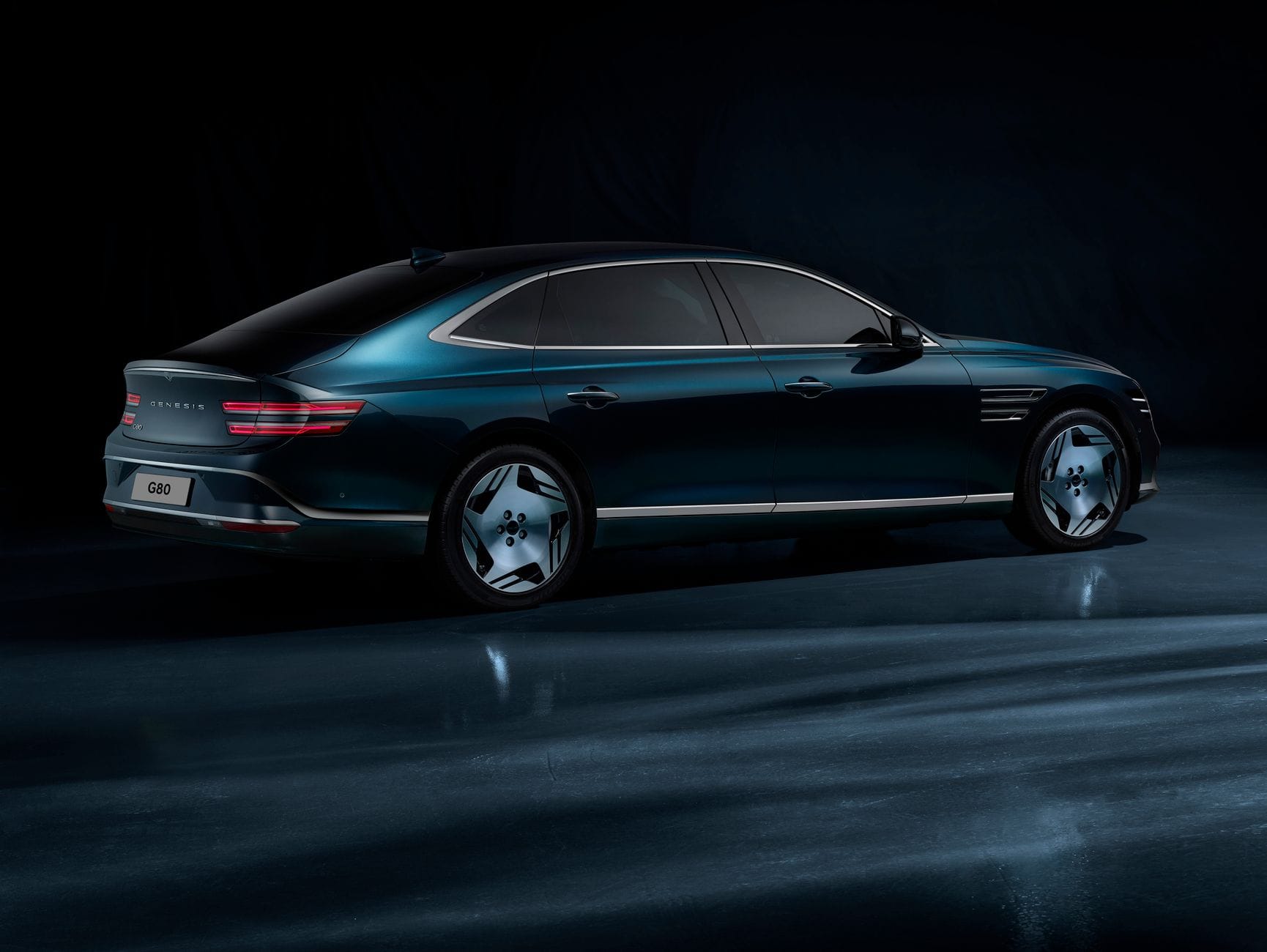 Tylny bok elektrycznego Genesis G80 w przyciemnionym studio