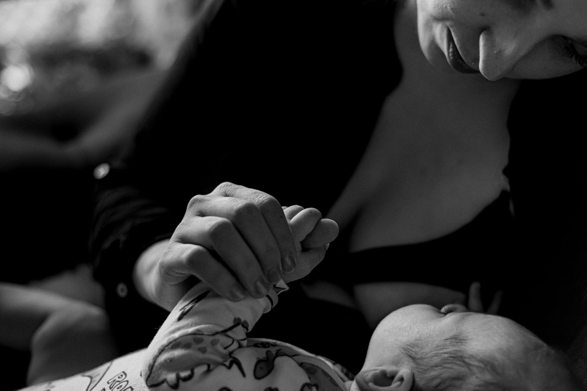 Mama trzyma za rękę niemowlę, czarno-białe zbliżenie dłoni